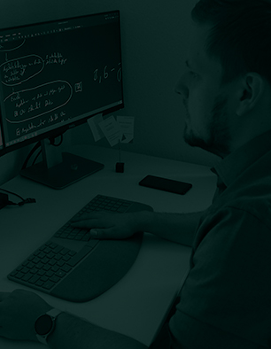 Eingefärbtes Foto von Herrn Stief (Inhaber) an seinem Arbeitsplatz. Auf dem Monitor vor ihm sind digitale Zeichnungen und Notizen zu sehen. Sein Schreibtisch folgt der Clean-Desk-Policy.